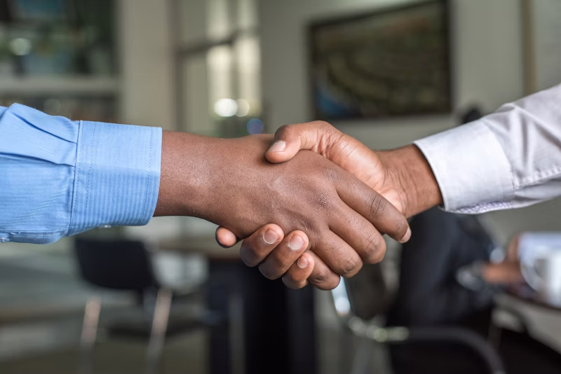 Two professionals shaking hands in an office setting, representing partnership and trust